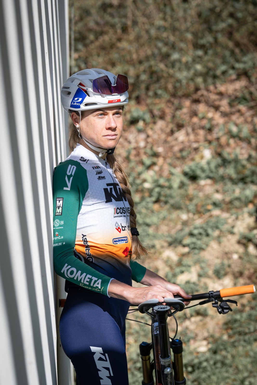 Mountainbike-Marathon-Weltmeisterin Anna Weinbeer lehnt an einer Wand, Blick in die Ferne