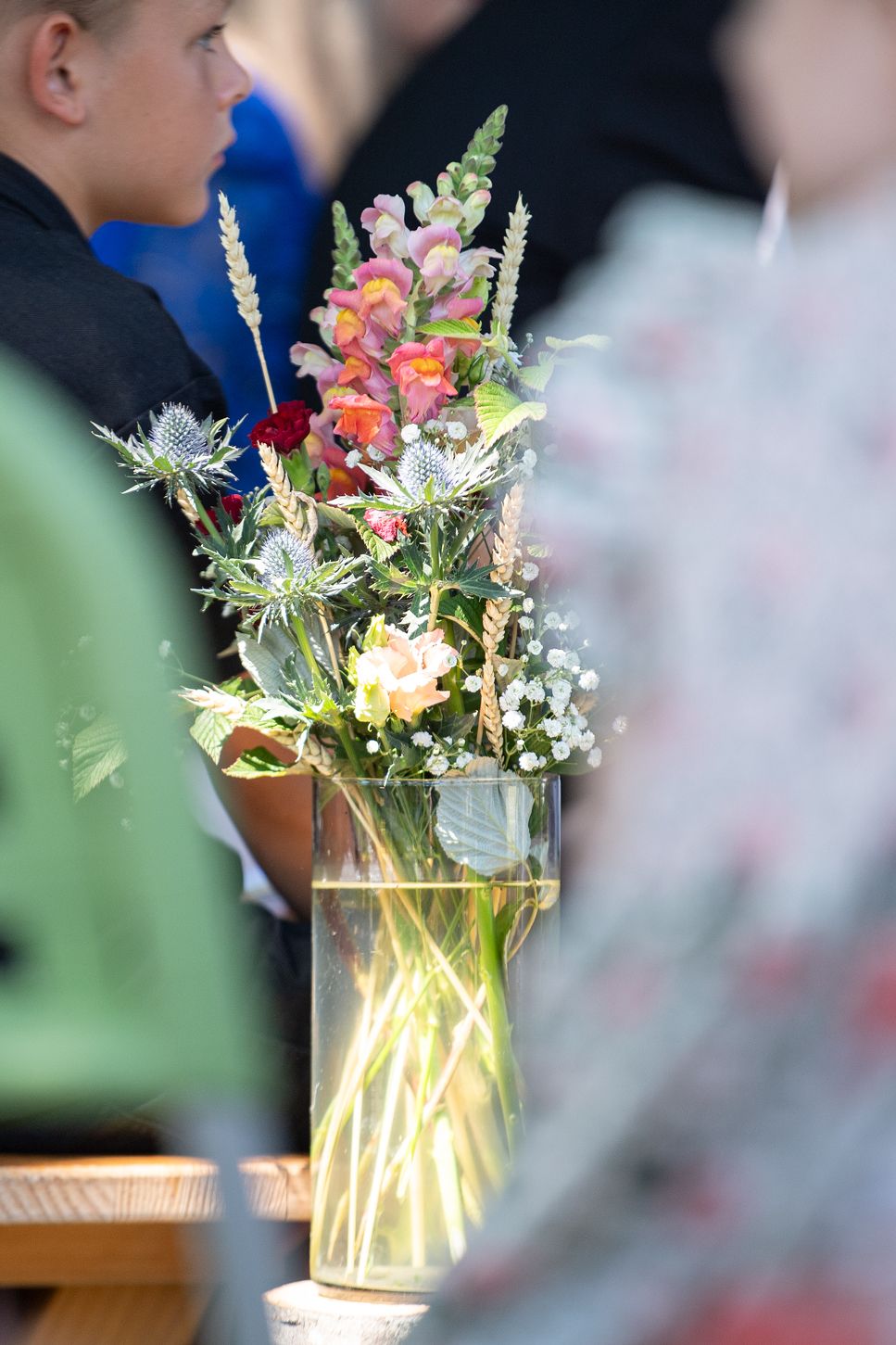 Wiesenblumen mit Ähren im Glas zwischen den Gästereihen