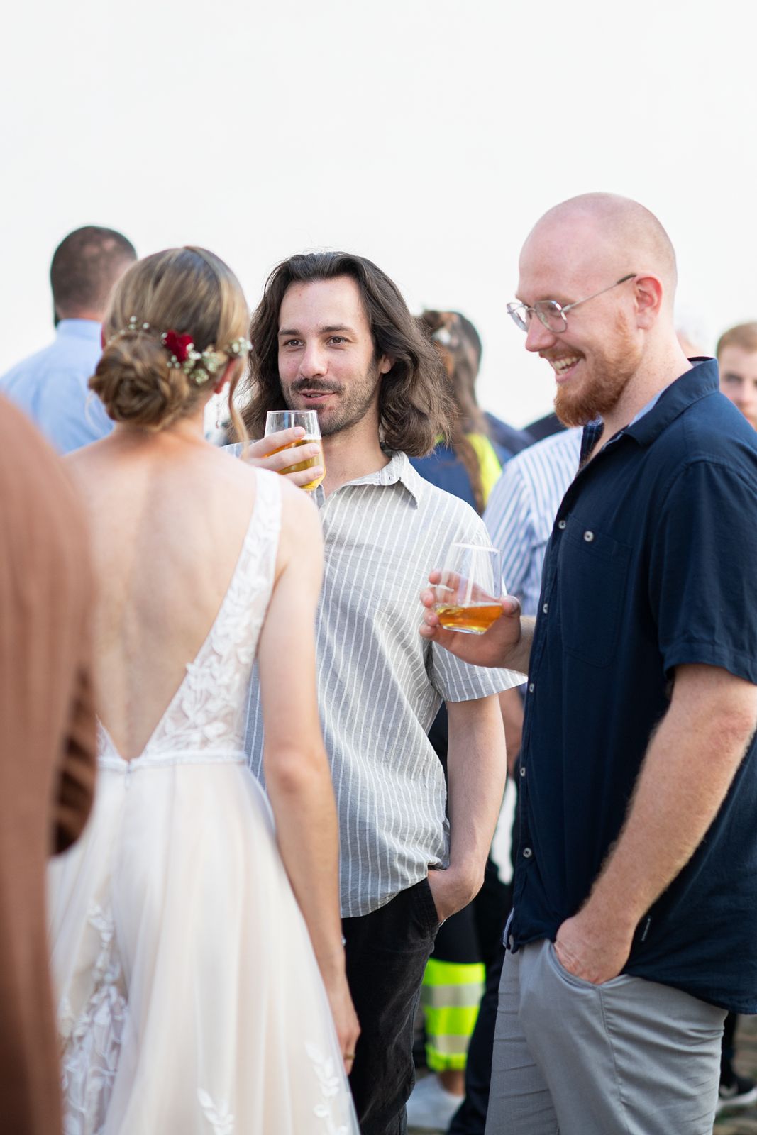 Braut im rückenfreien Kleid im Gespräch mit Gästen beim Apéro