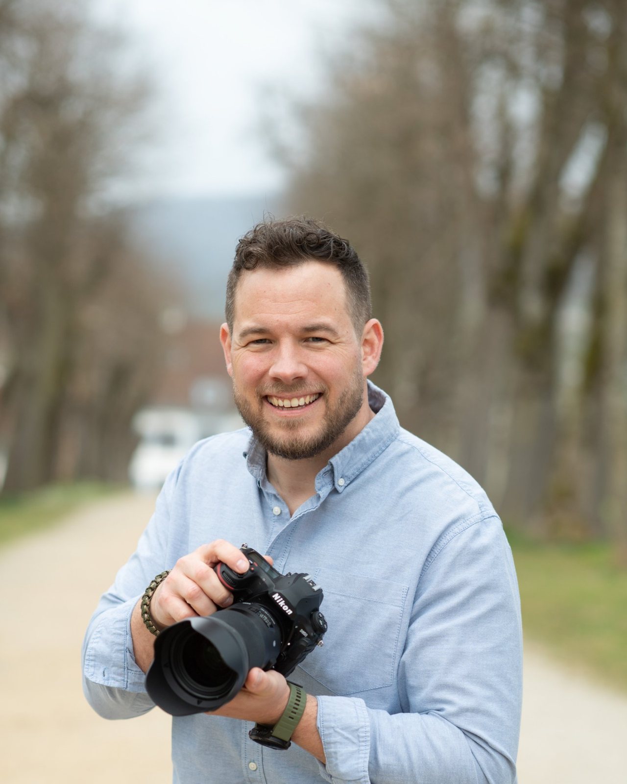 David Sigg lacht in die Kamera, mit seiner Nikon in der Hand