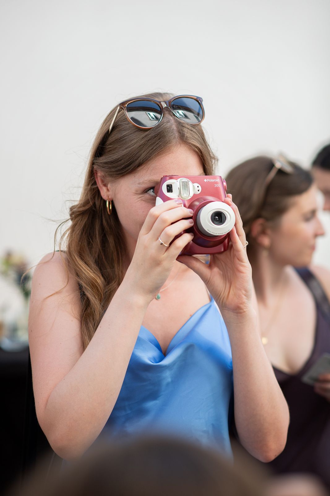 Hochzeitsgast fotografiert mit einer roten Polaroid-Kamera
