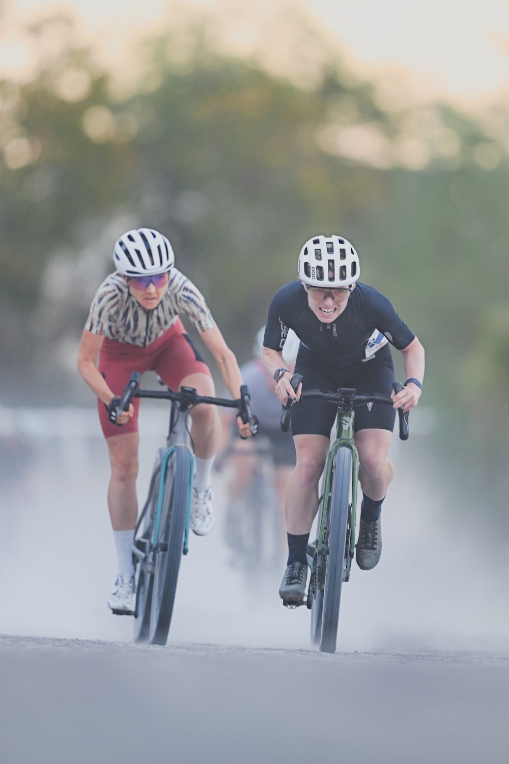 Zwei Gravel-Fahrerinnen im Sprint, hinter ihnen eine Staubwolke