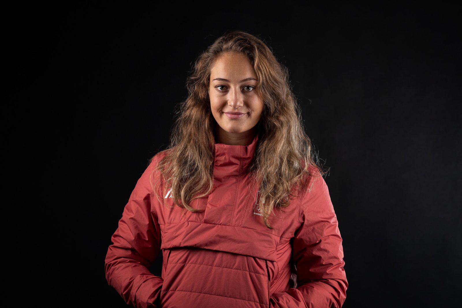 Snowboardcrosserin Sina Siegenthaler in roter Jacke vor schwarzem Hintergrund