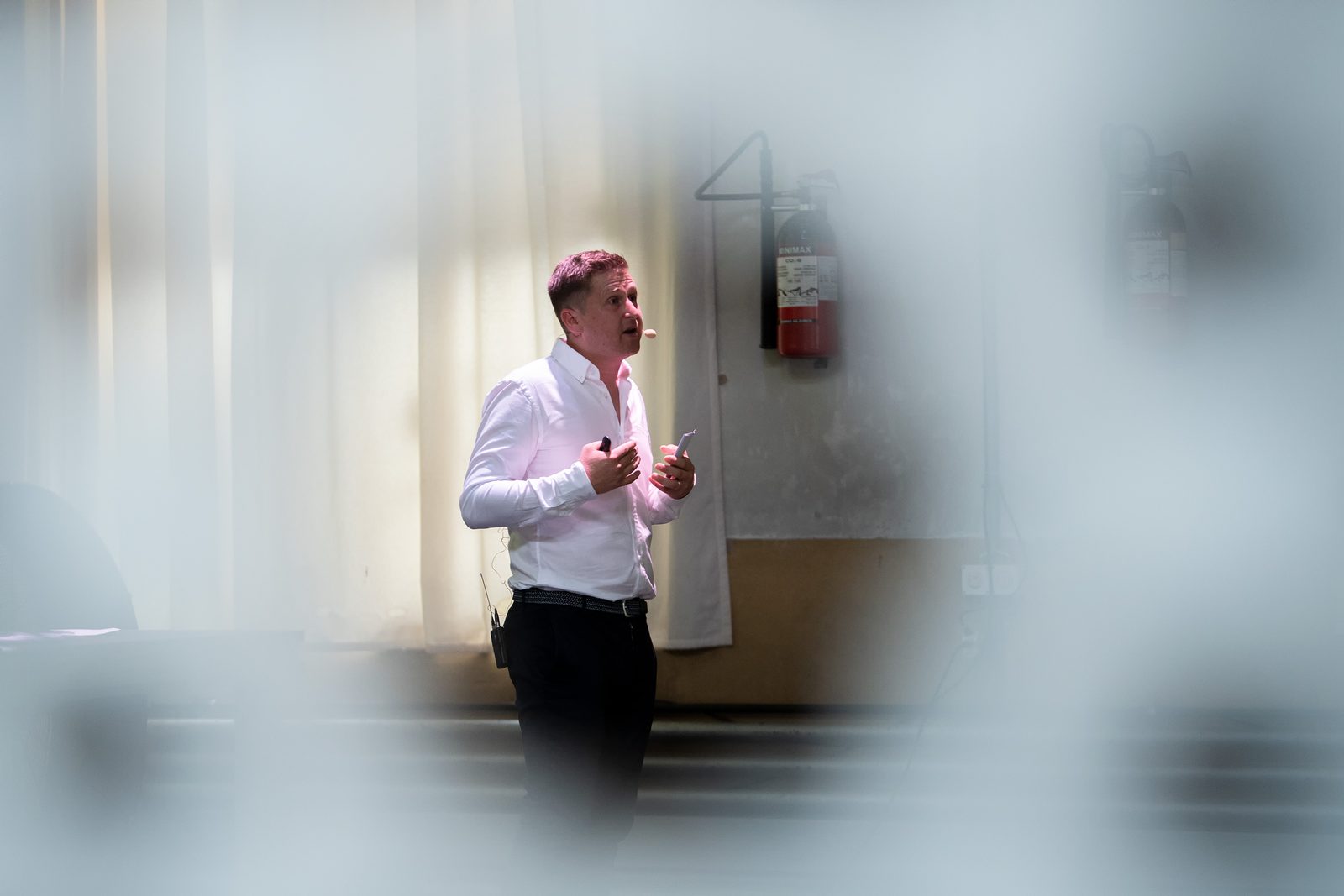 Redner auf der Bühne, durch eine unscharfe Glasfläche fotografiert